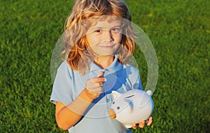 Portrait of cute little boy with piggy bank. Saving money concept. Kids with piggybank money box.