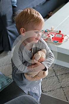 portrait of cute little boy playing with teddy bear in living room