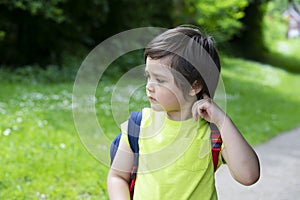 Portrait cute little boy scratching his itchy neck and looking down with thinking face, Kid get allergies while go out with school