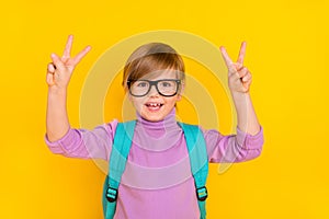 Portrait of cute little boy showing v-sign happy go to school 1-september first day  on yellow color background