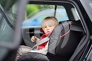 Portrait of cute little boy sitting in car seat. Child transportation safety