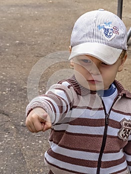 Portrait of a cute little boy in a t-shirt and a baseball cap having fun in the garden.