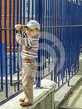 Portrait of a cute little boy in a t-shirt and a baseball cap having fun in the garden.