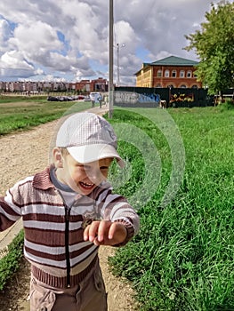 Portrait of a cute little boy in a t-shirt and a baseball cap having fun in the garden.