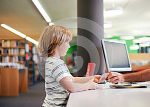 Portrait of cute little boy taking books in library