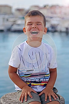 A portrait of a cute little boy who laughs on a warm summer day