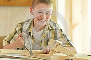 Portrait of cute little boy working with wood in workshop