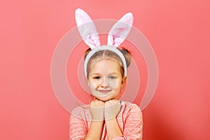 Portrait of a cute little child girl with bunny ears on a colar pink background. Easter concept. Close-up photo