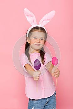 Cute little girl with Easter bunny ears holding colorful eggs