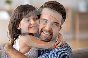 Portrait of cute little daughter hug young father photo