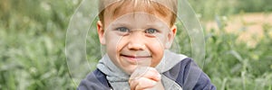 Portrait of a cute little four year old smiling happy candid european kid boy in nature in the garden in summer. banner.