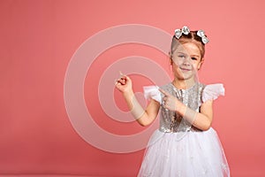 Portrait of a cute little girl in a beautiful dress that shows somewhere with her hands