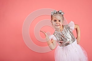 Portrait of a cute little girl in a beautiful dress that shows somewhere with her hands