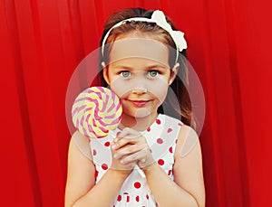 Portrait of cute little girl child with lollipop wearing a dress