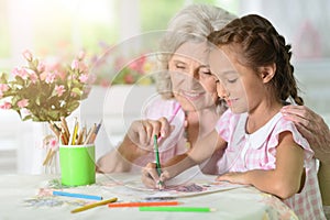 Portrait of a little girl drawing with her grandmother