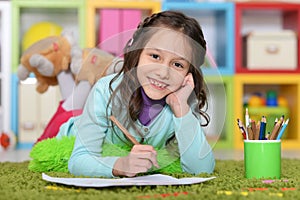 Portrait of cute little girl drawing while lying