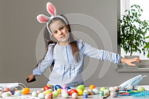 Portrait of a cute little girl dressed in Easter bunny ears holding colorful eggs.