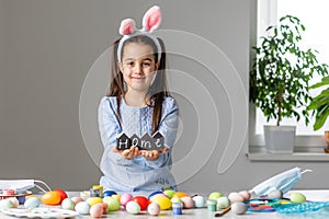 Portrait of a cute little girl dressed in Easter bunny ears holding colorful eggs.