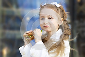 Portrait of cute little girl eating sandwich during break between classes. healthy unhealthy food for kid