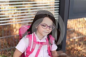 Portrait of a cute little girl with glasses and a pink backpack