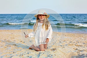 Portrait of a cute little girl in a hat on the beach