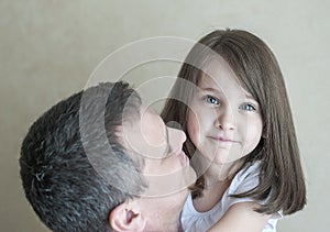 Portrait of cute little girl held in father`s arms. Happy loving family. Father and his daughter child girl playing hugging