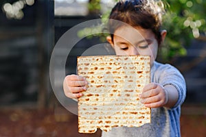Portrait of the cute little girl holding matzah. Jewish child eating matzo in Jewish holidays Passover.