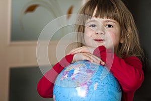 Portrait of the cute little girl hugging the earth globe. Education and save the earth concept. Pretty child looking in the camera