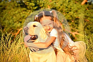 Portrait of a cute little girl hugging a labrador dog