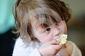 Portrait of a cute little girl inside eating potato chip with sour cream dip on it