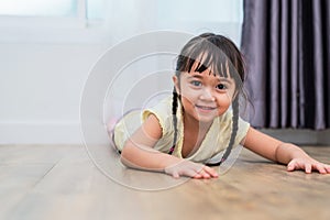 Portrait of cute little girl lying on floor with barefoot and looking at camera at home. People lifestyles concept