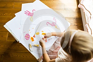 Portrait of a cute little girl painting hands at home. Learn, education, happy childhood concept