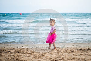 Portrait of cute little girl with pink dress on the beach