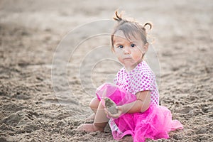Portrait of cute little girl with pink dress on the beach