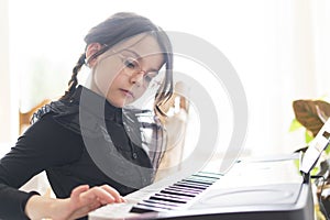 Portrait of a cute little girl playing the keyboard at home