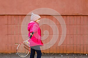 Portrait of a cute little girl playing tennis.