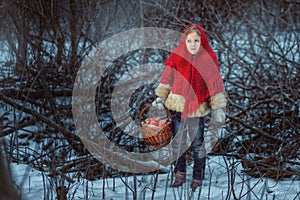 Portrait of a cute little girl in a red fur coat in the winter forest