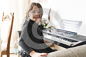 Portrait of a cute little girl sitting at home and playing the piano