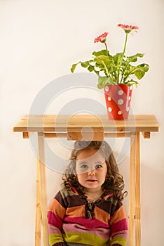 Portrait of a cute little girl sitting under the table