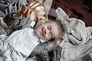 Portrait of a cute little girl in a sweater with a leaf in her hands