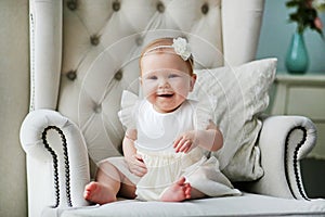 Portrait of a cute little girl in a white dress in a home light interior.