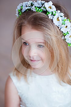 Portrait of a cute little girl in wreath of flowers