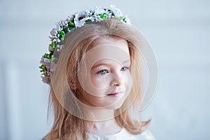 Portrait of a cute little girl in wreath of flowers