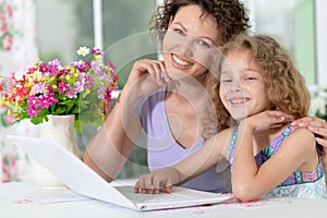 Cute little girl with young mother using laptop