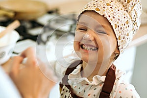 Portrait of cute little homecook girl in white kitchen