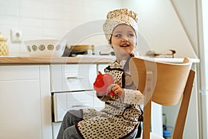 Portrait of cute little homecook girl in white kitchen