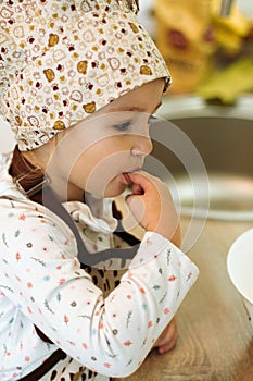 Portrait of cute little homecook girl in white kitchen