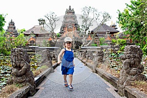 Portrait of a cute little kid with Pura Taman Saraswati temple on background, Ubud, Bali, Indonesia