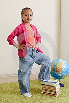Portrait of cute little latin schoolgirl in classroom. Happy young latin girl wearing casual clothing