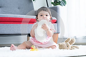Portrait of cute little 7 months old multiracial, asian and caucasian, newborn baby girl sitting on floor having teeth growing